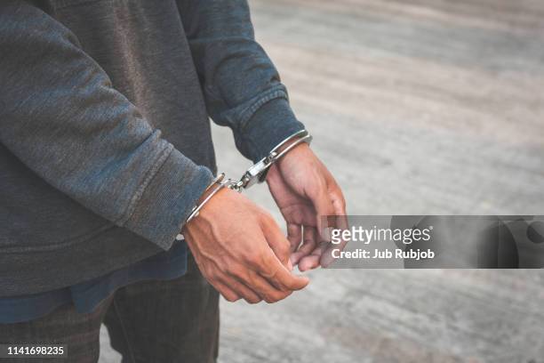 arrested businessman handcuffed hands. close-up. - handcuffs stock-fotos und bilder
