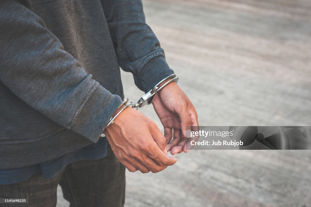 Arrested businessman handcuffed hands. Close-up.