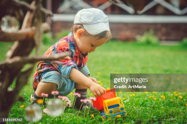 happy child playing with toy car at back yard - toy truck stock pictures, royalty-free photos & images