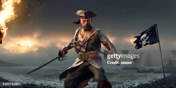 fierce pirate standing on beach with cutlases and jolly roger - pirata imagens e fotografias de stock