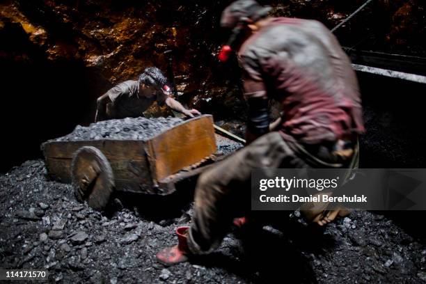 Year old Anil Basnet pushes a coal cart, as he and a fellow worker pull coal out from the rat hole tunnel 300 ft below the surface on April 13, 2011...