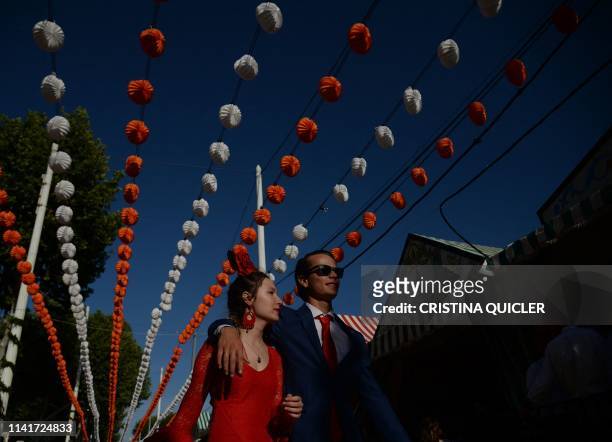 Couple walks past "casetas" during the "Feria de Abril" festival in Seville on May 6, 2019. - The fair dates back to 1847 when it was originally...