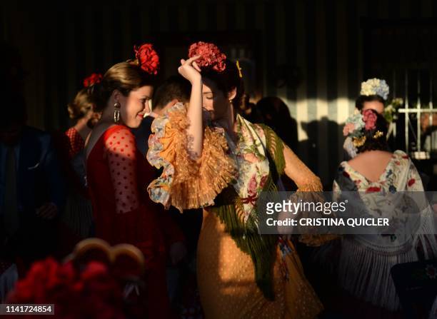 Women in traditional Sevillian dresses dance in a "caseta" during the "Feria de Abril" festival in Seville on May 6, 2019. - The fair dates back to...