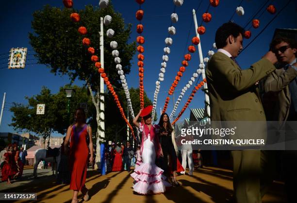 People in traditional Sevillian costumes walk along the street during the "Feria de Abril" festival in Seville on May 6, 2019. - The fair dates back...