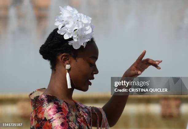 Tourist in traditional Sevillian dresse poses for a photo at the Plaza de Espana square during the "Feria de Abril" festival in Seville on May 6,...