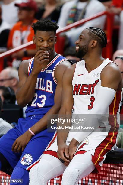 Dwyane Wade of the Miami Heat talks with Jimmy Butler of the Philadelphia 76ers as they wait to check in to the game at the scorers table during the...