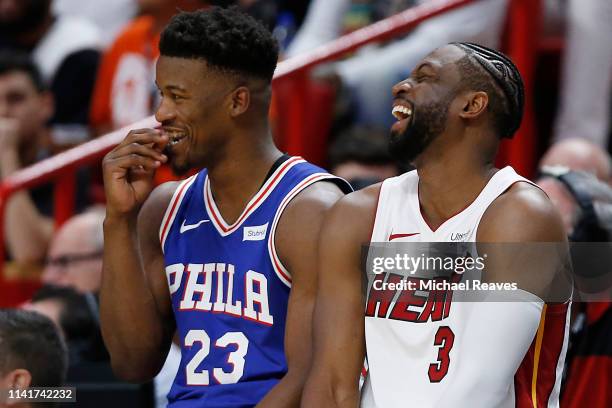 Dwyane Wade of the Miami Heat talks with Jimmy Butler of the Philadelphia 76ers as they wait to check in to the game at the scorers table during the...