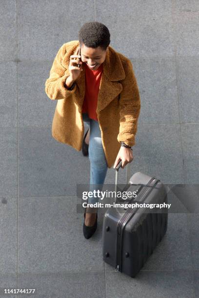 above of young african american travel woman walking and talking with cellphone on city street