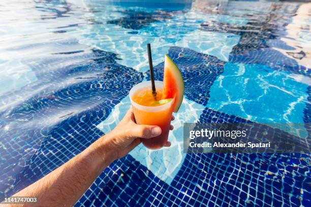 drinking watermelon cocktail in the swimming pool - swimming pool and hand stock pictures, royalty-free photos & images