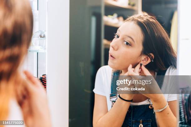 joven adolescente poniendo aretes en - earring fotografías e imágenes de stock