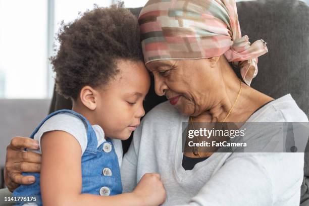senior woman with cancer lovingly holds granddaughter - woman home with sick children imagens e fotografias de stock