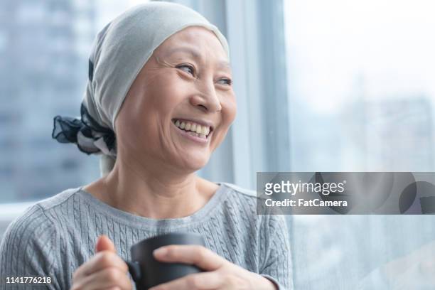 hermosa mujer coreana con cáncer mira hacia fuera ventana - cancer survivor fotografías e imágenes de stock