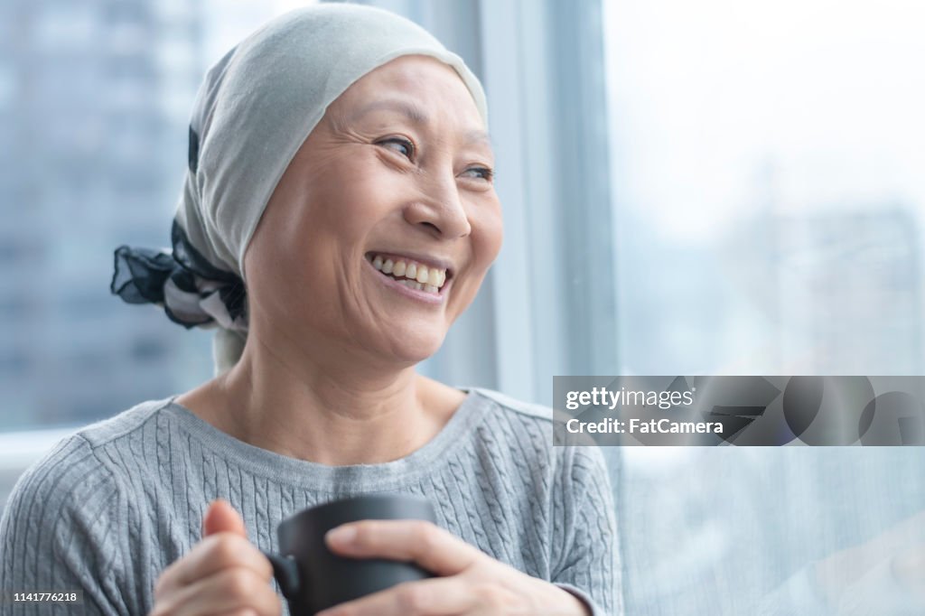 Bella donna coreana con il cancro guarda fuori dalla finestra