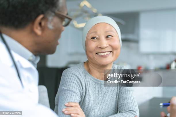 schöne koreanerin mit krebs lächelt beim arzt - cancer patient stock-fotos und bilder