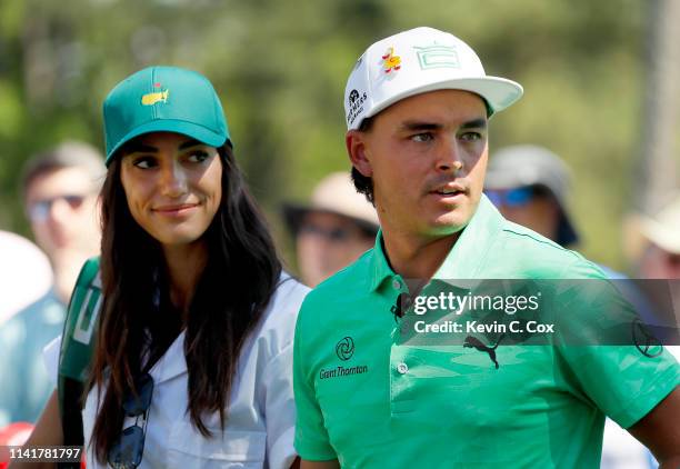 Rickie Fowler of the United States stands with fiancee Allison Stokke during the Par 3 Contest prior to the Masters at Augusta National Golf Club on...