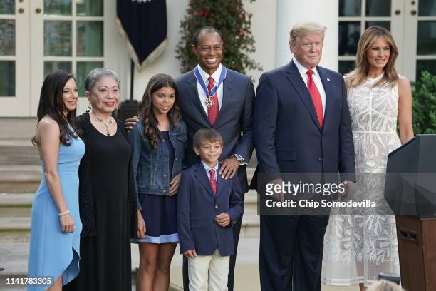 President Donald Trump and First Lady Melania Trump pose for photos with professional golfer and business partner Tiger Woods and his family after...