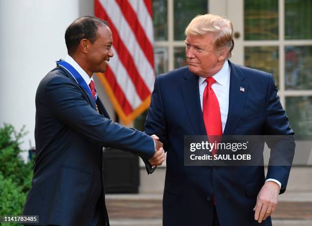 President Donald Trump and US golfer Tiger Woods shake hands after Trump awarded him with the Presidential Medal of Freedom during a ceremony in the...