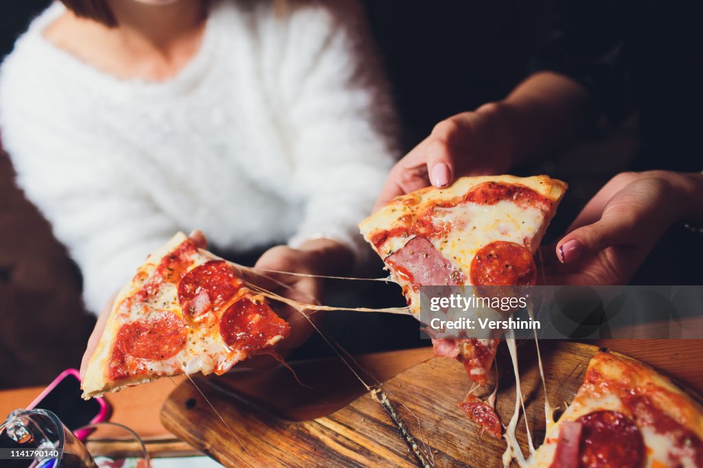 High angle shot of a group of unrecognizable people's hands each grabbing a slice of pizza.