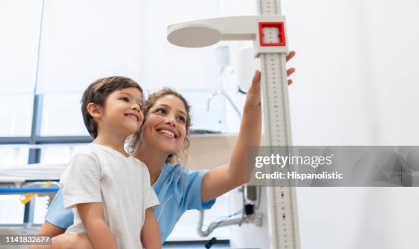 sweet nurse and boy looking at how much he is grown both very happy - pediatric imagens e fotografias de stock