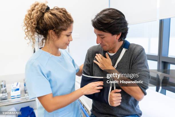 enfermera ajustando los pacientes para inmovilizar su brazo en el hospital - cabestrillo de brazo fotografías e imágenes de stock