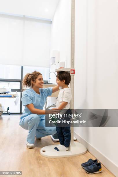 cute little patient and happy nurse measuring him to check how much he has grown - altitude sickness stock pictures, royalty-free photos & images