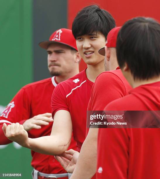 The Los Angeles Angels' two-way player Shohei Ohtani shows teammates his right-elbow scar after Tommy John surgery, at the team's spring training...