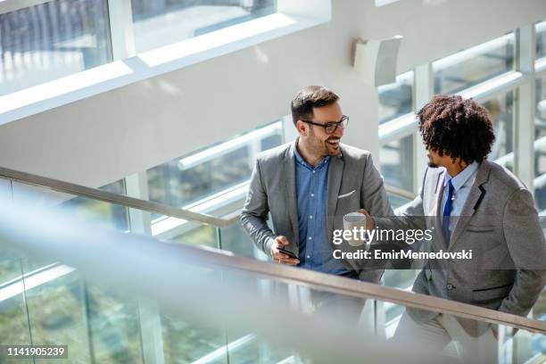 due colleghi di lavoro che parlano mentre salgono le scale - salire le scale foto e immagini stock