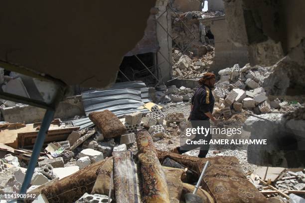 Man walks amidst the rubble of a building, destroyed during airstrikes by the Syrian regime and their allies near the town of Saraqeb in Syria's...