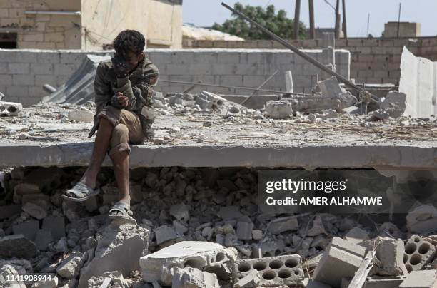 Man sits amidst the rubble of a building, destroyed during airstrikes by the Syrian regime and their allies near the town of Saraqeb in Syria's...