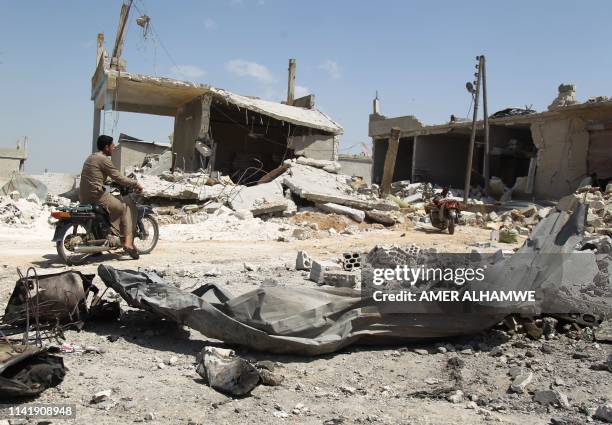 Man drives his motorcycle on street that was hit during airstrikes by the Syrian regime and their allies near the town of Saraqeb in Syria's...