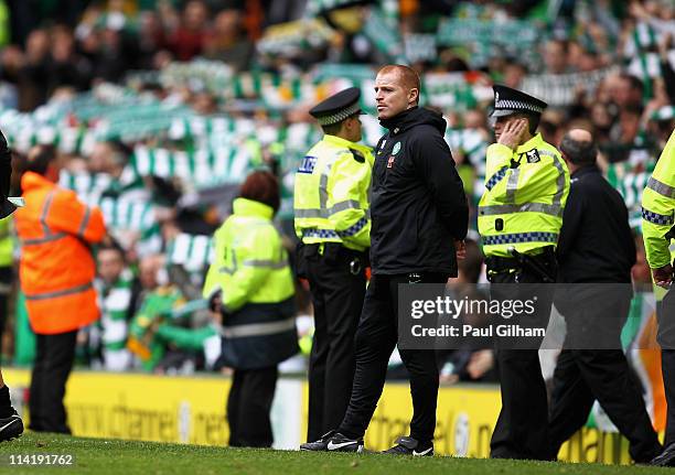 Manager Neil Lennon of Celtic flanked by police officers looks on as the crowd sing 'You'll never walk alone' at the end of the Clydesdale Bank...