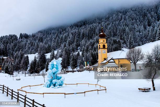 Ice fountain and church. Soraga. Val di Fassa. Trentino Alto Adige. Italy. Europe.