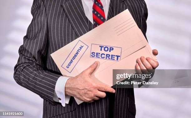 businessman holding confidential top secret folder - funcionario fotografías e imágenes de stock