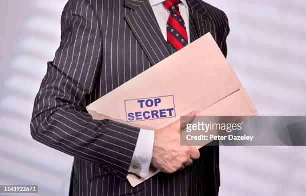 businessman holding confidential top secret folder - confidential mot anglais photos et images de collection