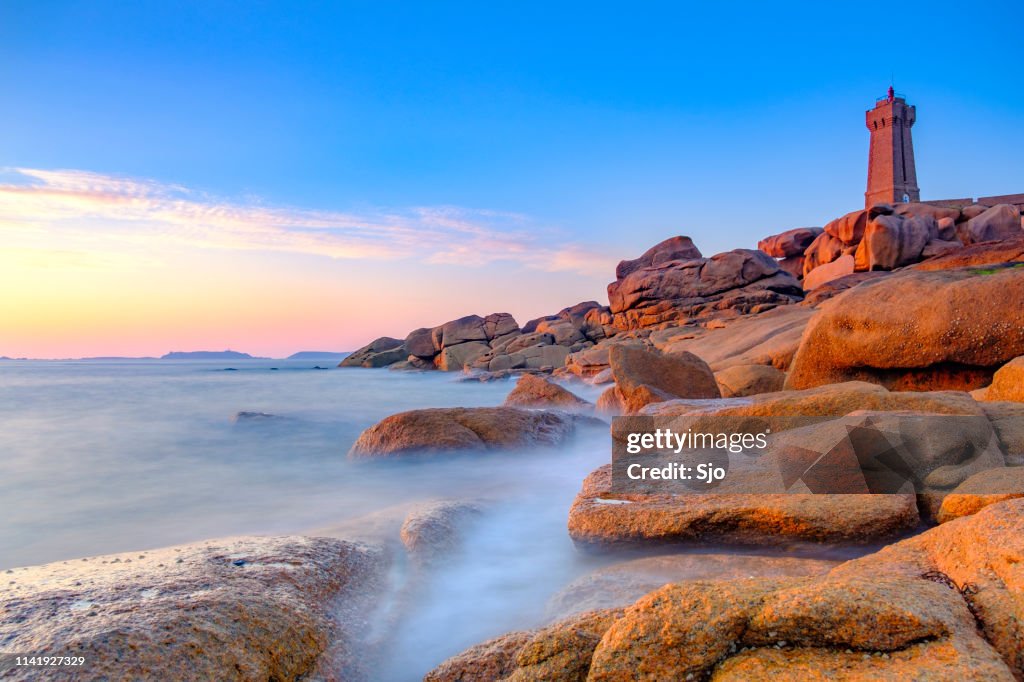 Ploumanach lighthouse at the pink granite coast in Brittany, France during sunset
