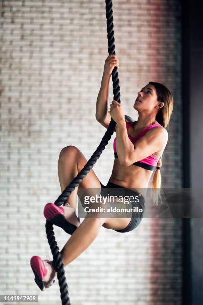Fit young woman climbing a rope as her exercise training