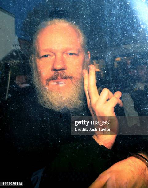 Julian Assange gestures to the media from a police vehicle on his arrival at Westminster Magistrates court on April 11, 2019 in London, England....