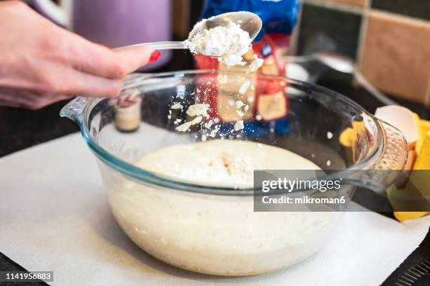 woman pouring flour into mixing bowl in kitchen. baking cake at home - esslöffel stock-fotos und bilder
