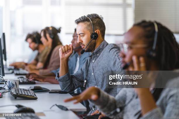 el ejecutivo escucha la consulta del cliente en los auriculares - call center serious fotografías e imágenes de stock