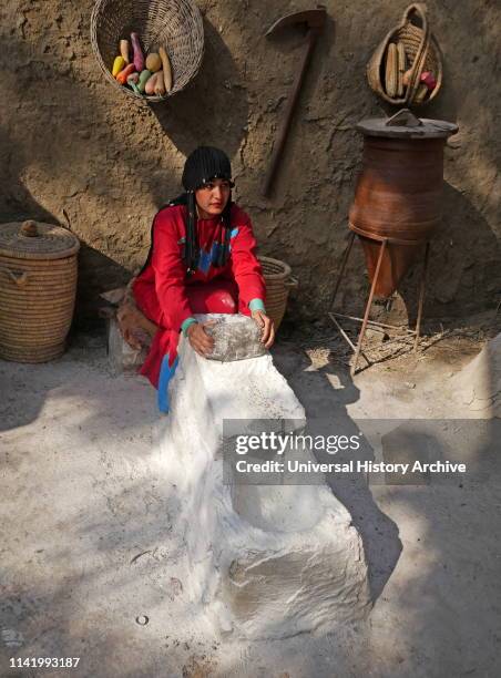 Model of a woman grinding corn for making bread in ancient Egypt.