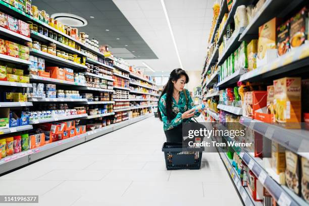 young woman kneeling looking at food items - asian market stock-fotos und bilder