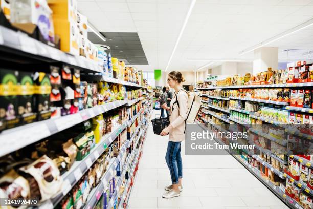 supermarket aisle with people grocery shopping - consumerism stock pictures, royalty-free photos & images
