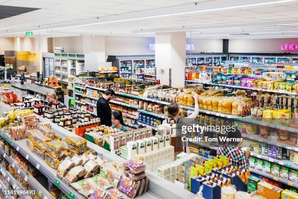 a busy supermarket with customers shopping - supermercado fotografías e imágenes de stock