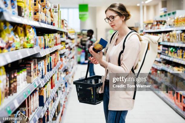 woman reading food item label in supermarket - shops photos et images de collection