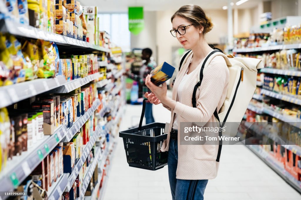 Woman Reading Food Item Label In Supermarket