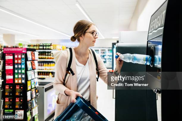 young woman recycling bottles at the supermarket - recycling ストックフォトと画像