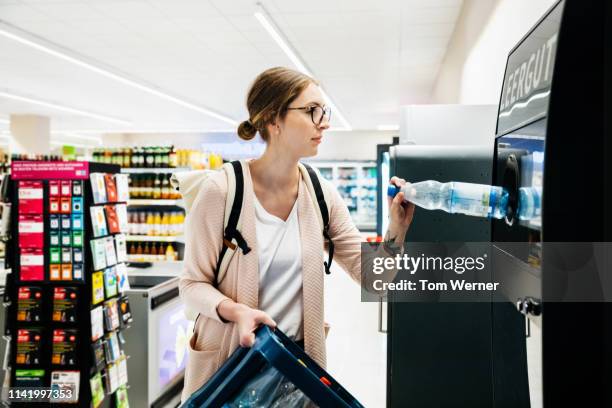 young woman recycling bottles at the supermarket - lots of bottles stockfoto's en -beelden