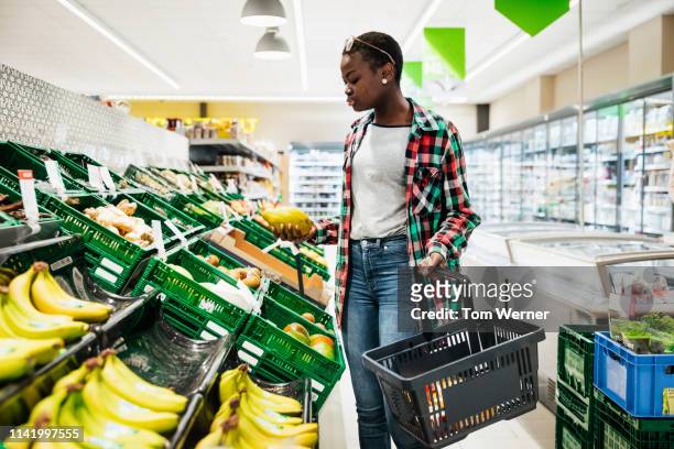 young woman shopping for fruit at supermarket - supermarket fruit stock-fotos und bilder