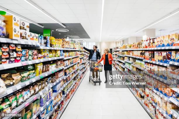 mature couple with shopping cart picking up groceries. - supermarktgang stock-fotos und bilder
