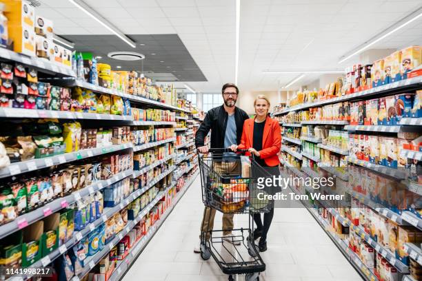 portrait of mature couple shopping in supermarket - 40 44 jahre paar stehend ganzkörper stock-fotos und bilder